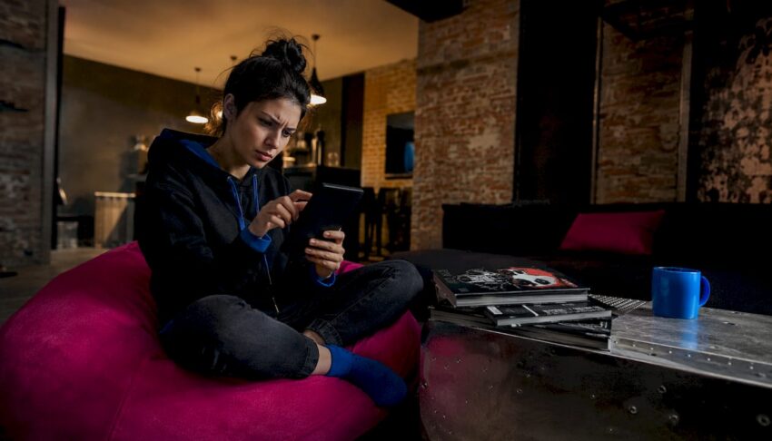 Woman using Kindle Unlimited on sofa