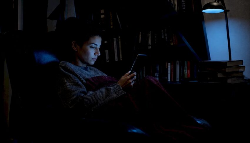 Woman reading dark fiction on Kindle at night