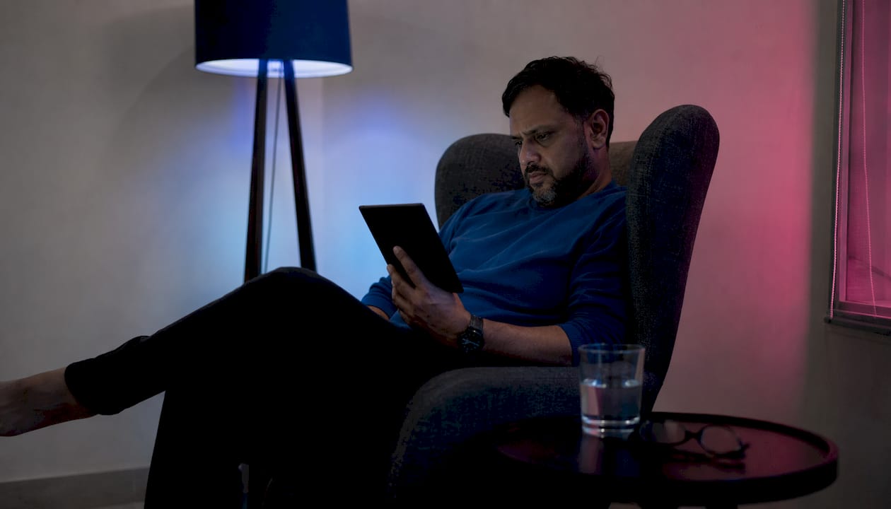 Man reading horror thriller e-reader in cozy library nook