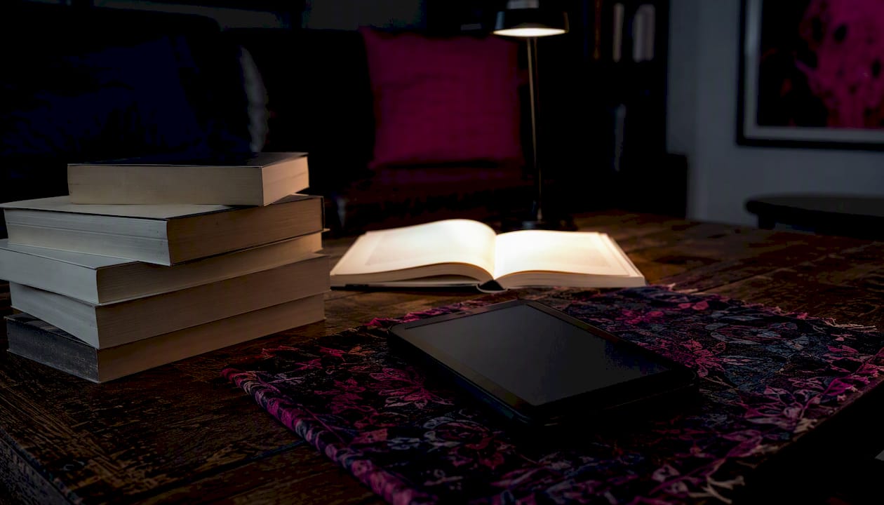 Overhead view of book stack and Kindle on desk