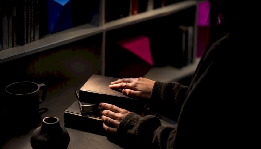 Hands holding existential horror book in dark nook