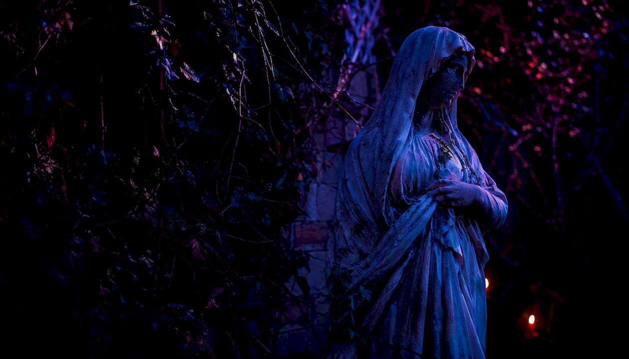 Shadowed gothic statue under moonlight