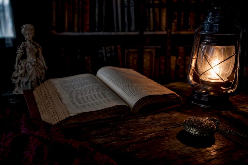 Open horror novel with candlelight in dim library
