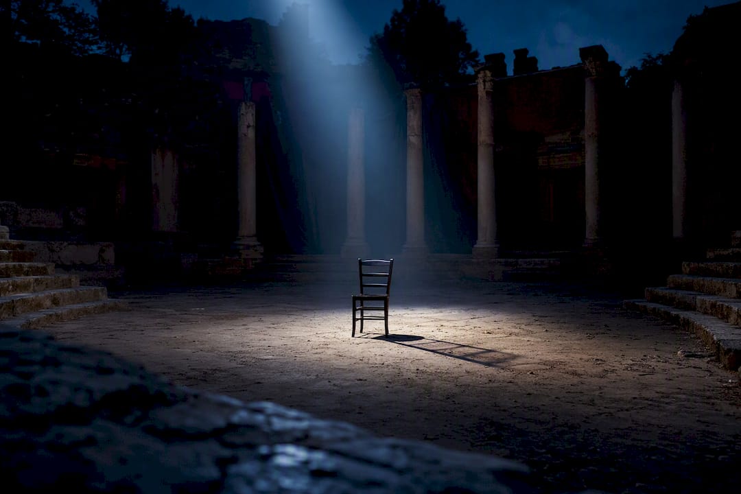Empty stage with wooden chair and dramatic shadows