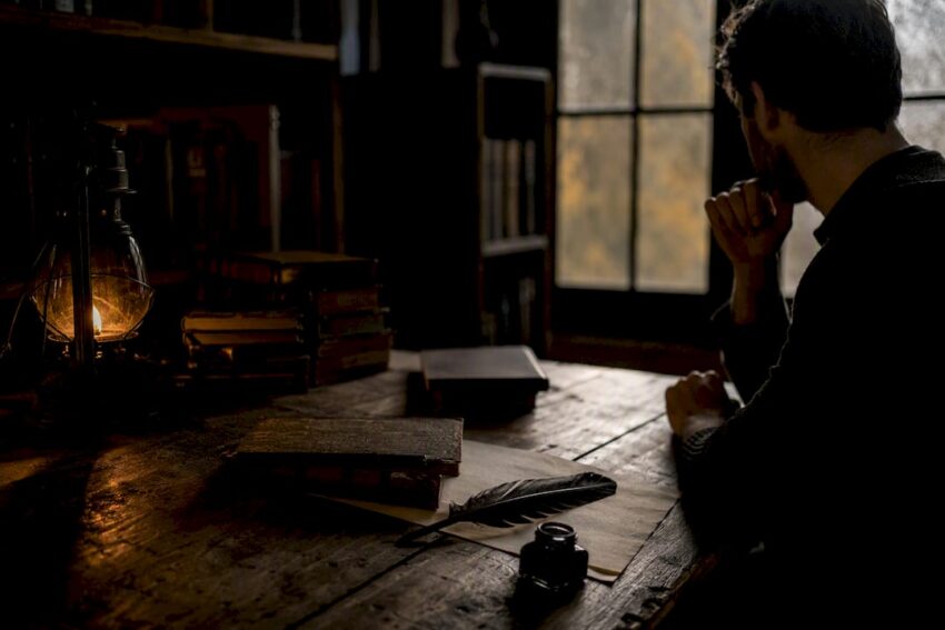Dark wooden desk with revenge-themed books and candle