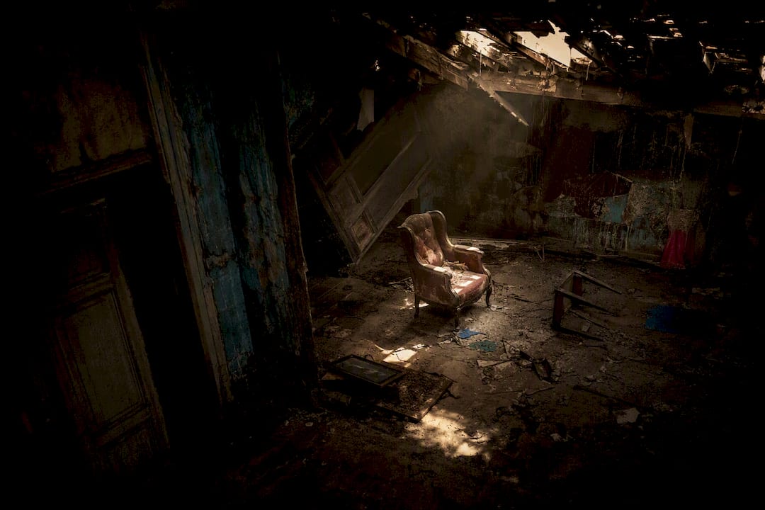 Dimly lit haunted room with old chair