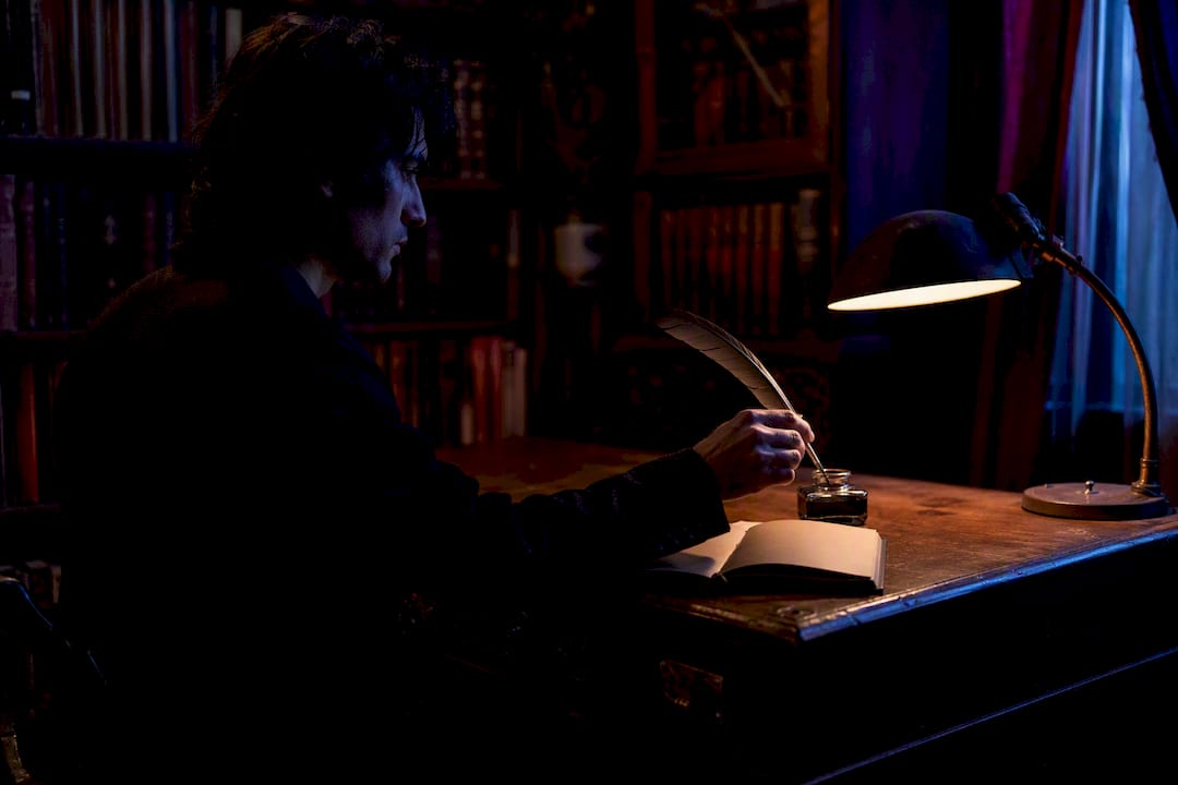 Quill dipping into ink on writer's desk