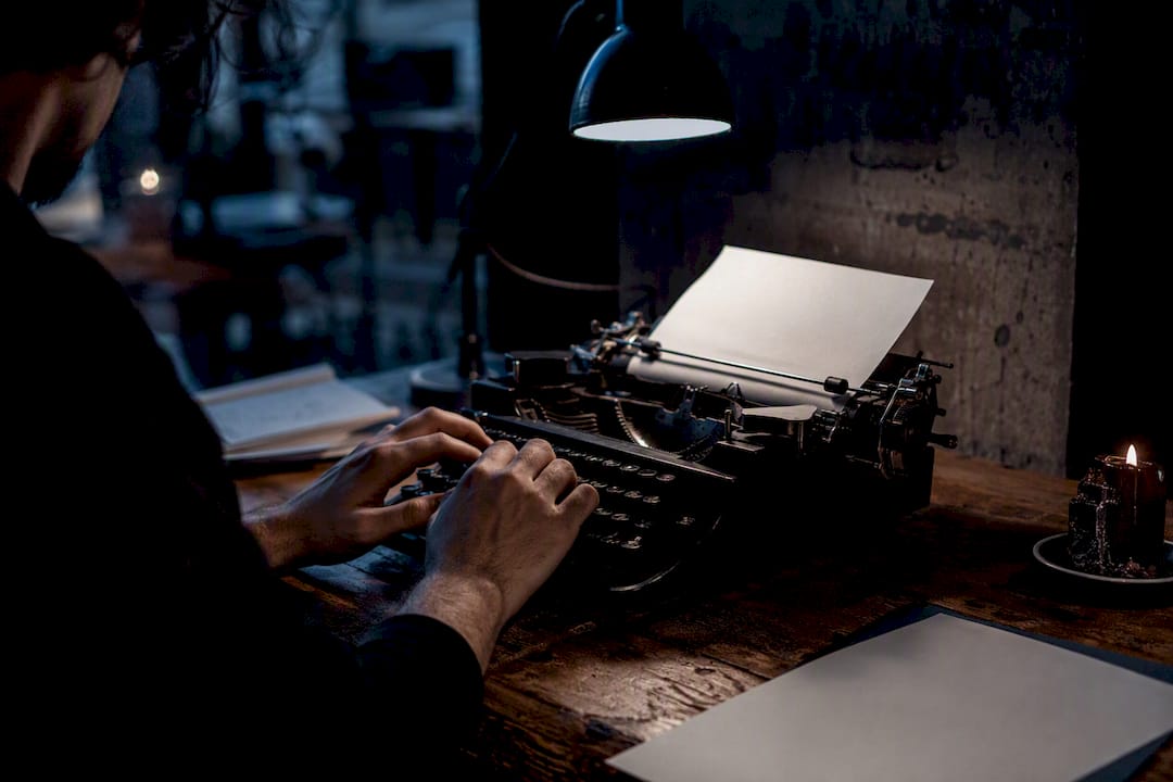 Hands typing thriller on typewriter
