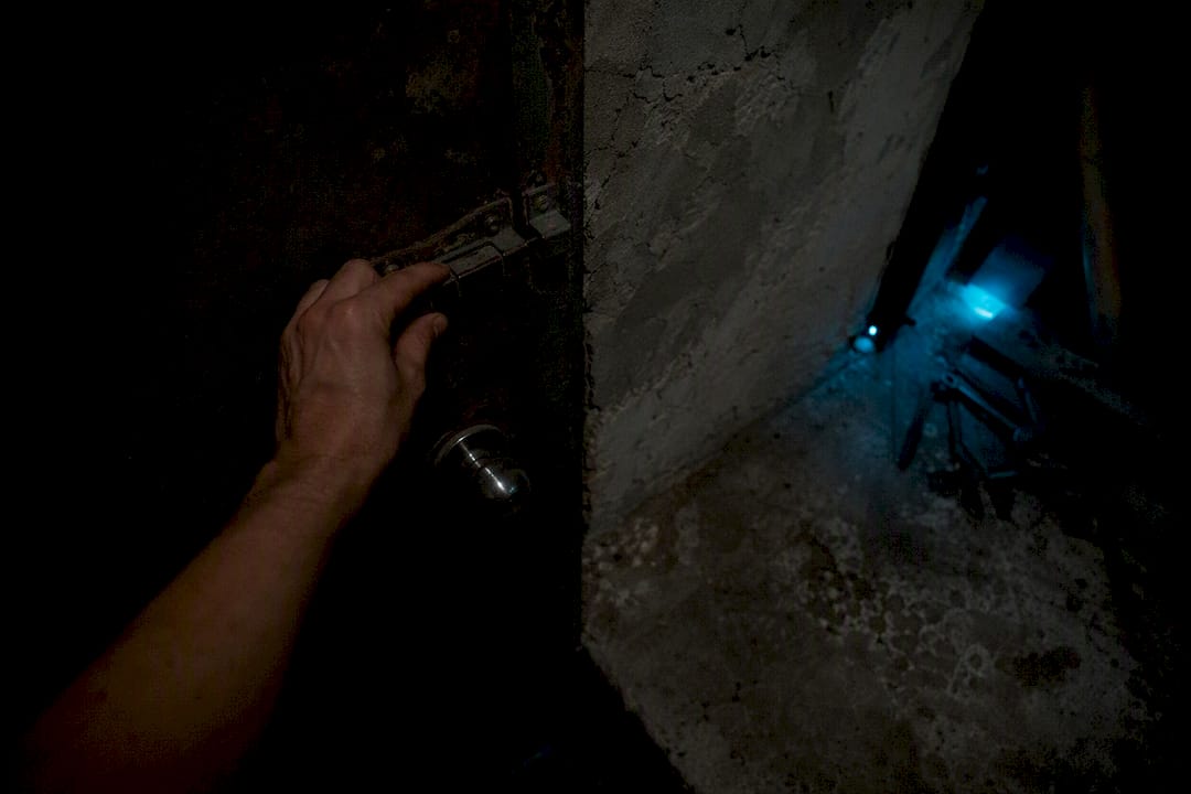 Hand locking old door in dim hallway