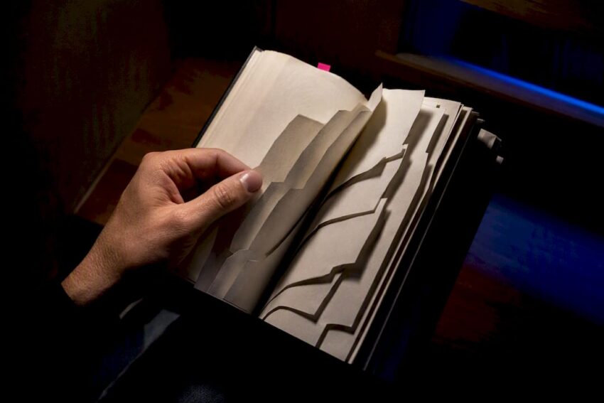 Hand turning fragmented horror novel pages