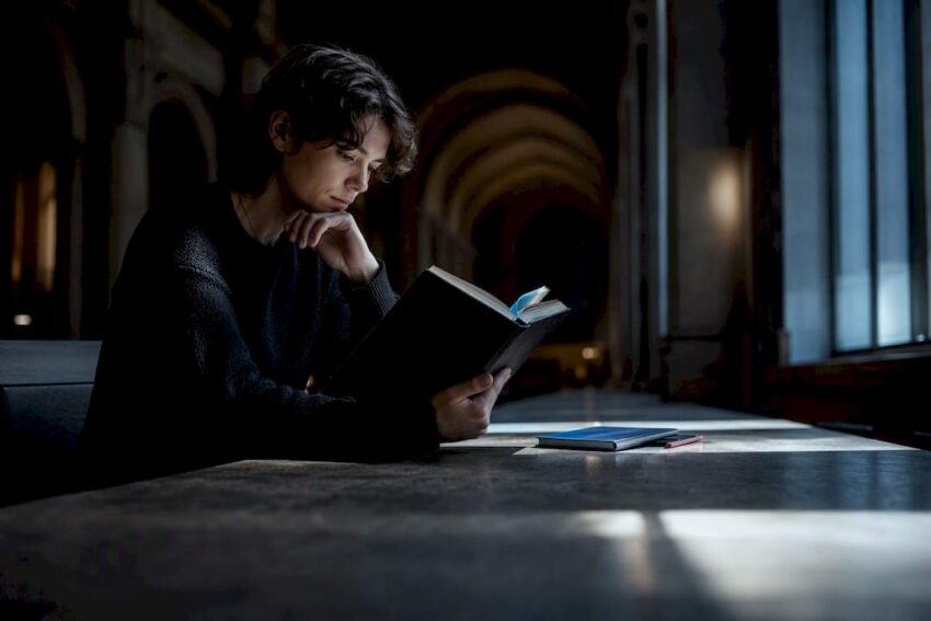 Reader studying a horror novel in shadow