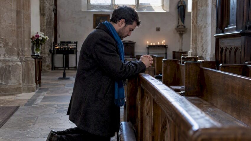Person kneeling in a quiet chapel